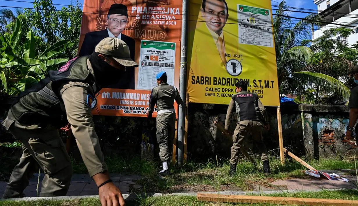 Petugas Satpol PP mencopot ratusan APK dan bendera partai yang terpasang tak sesuai aturan. (CHAIDEER MAHYUDDIN/AFP)