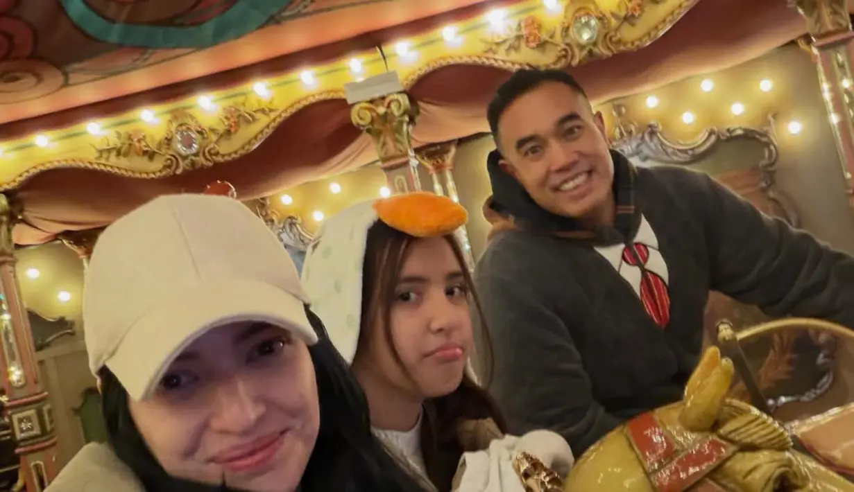 Dalam balutan busana musim dingin, Nia Ramadhani dan Mikhayla bermain carousel di wahana taman bermain [@ramadhaniabakrie]