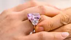 Seorang perempuan memamerkan berlian Sakura 15,81 karat selama pratinjau pra-lelang Christies di Hong Kong pada 20 Mei 2021. Berlian ungu berkelir merah muda yang terlihat sangat cerah dilelang seharga USD38 juta atau sekitar Rp539 miliar di Hongkong pada hari Minggu mendatang. (Anthony WALLACE/AFP)