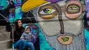 Seniman Cynthia Aguilera berpose bersama putranya di sebelah mural buatannya di Valparaiso, Chile, 9 April 2019. Selama beberapa tahun terakhir, tembok di sepanjang Elias Street di Valparaiso diubah menjadi kanvas raksasa tempat seniman jalanan memamerkan keterampilan mereka. (Martin BERNETTI/AFP)