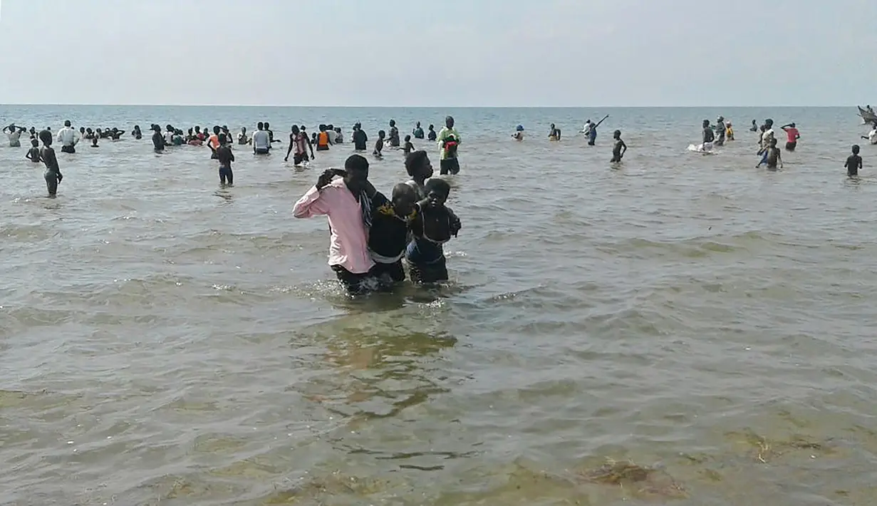 Warga membantu seorang pria yang selamat dari tenggelamnya kapal di Danau Albert, Butiaba, Uganda, Senin (26/12). Kelebihan muatan, dengan jumlah penumpang mencapai 45 orang membuat perahu menjadi tak seimbang hingga akhirnya terbalik. (AFP Photo)