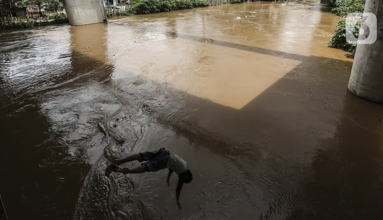 Seorang anak melompat ke Sungai Ciliwung saat banjir melanda Jalan Bina Warga Rt 005/Rw 07 Kelurahan Rawa Jati, Jakarta, Senin (8/2/2021). Banjir setinggi 60-190 cm tersebut disebabkan oleh luapan air Sungai Ciliwung dan curah hujan Jakarta yang tinggi. (Liputan6.com/Johan Tallo)
