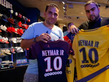 Suporter PSG menunjukkan jersey penyerang Neymar Jr di toko Paris Saint Germain di Paris (4/8). PSG resmi membeli Neymar dari Barcelona setelah menebus klausul pelepasan kontrak senilai 222 juta Euro, atau sekitar Rp 3,5 triliun. (AP Photo/Michel Euler)