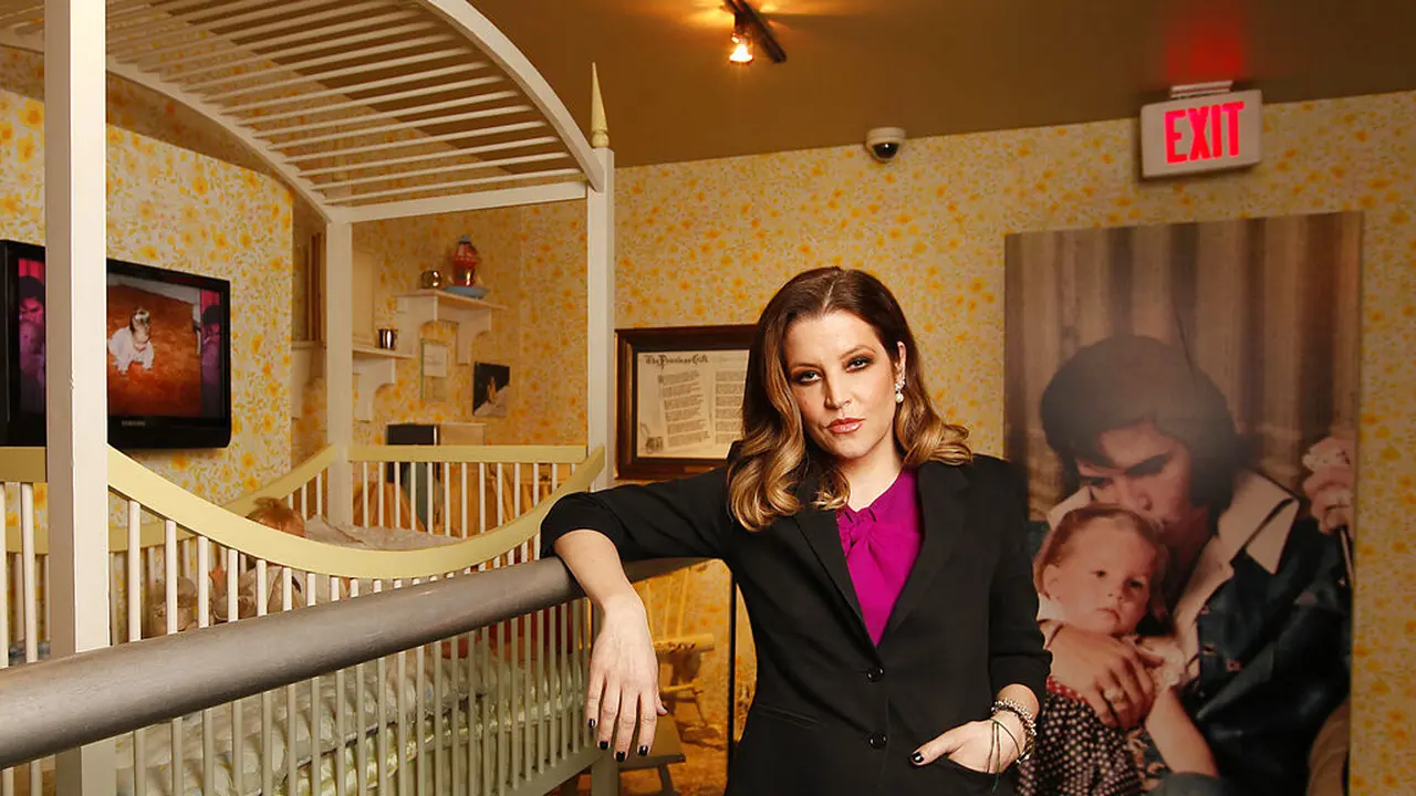 Lisa Marie Presley dengan ranjang bayi miliknya. Di belakangnya, adalah fotonya dengan Elvis Presley. AP Photo/Lance Murphey, File)
