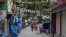 Pekerja berupah harian berjalan melewati jendela toko yang tutup di Dharmsala, India, Rabu (5/5/2021). Pemerintah India menghadapi seruan penguncian ketat atau lockdown nasional secara total untuk memperlambat gelombang besar infeksi virus corona. (AP Photo/Ashwini Bhatia)