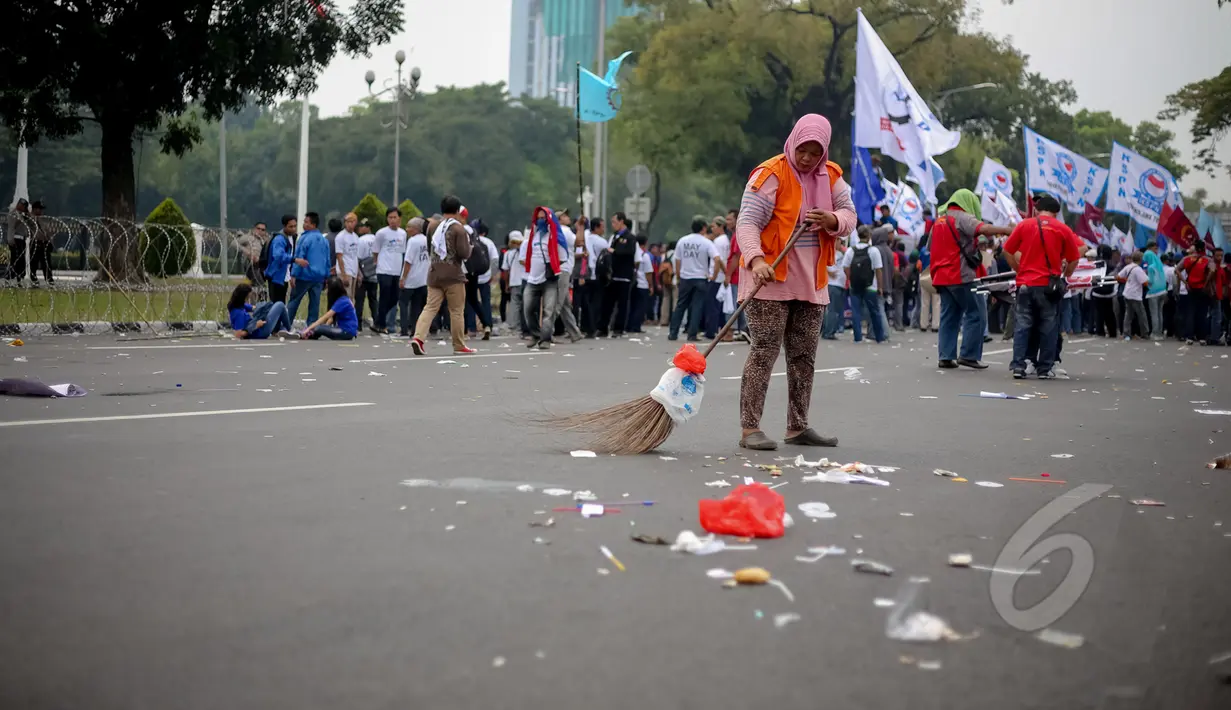 Petugas kebersihan membersihkan sampah saat peringatan hari buruh sedunia yang jatuh pada tanggal 1 Mei di depan Istana Merdeka, Jakarta, Jumat (1/5/2015). Aksi demo May Day menyisahkan sejumlah sampah berserakan di jalan. (Liputan6.com/Faizal Fanani)