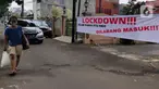 Pejalan kaki melintas di depan spanduk pemberitahuan lockdown di RT 04 / RW 09 Kelurahan Pondok Karya, Tangerang Selatan, Rabu (23/6). Melonjaknya kasus covid-19 di beberapa kawasan membuat sejumlah wilayah melakukan karantina di tingkat RT untuk memutus penyebaran corona (Liputan6.com/Angga Yuniar)