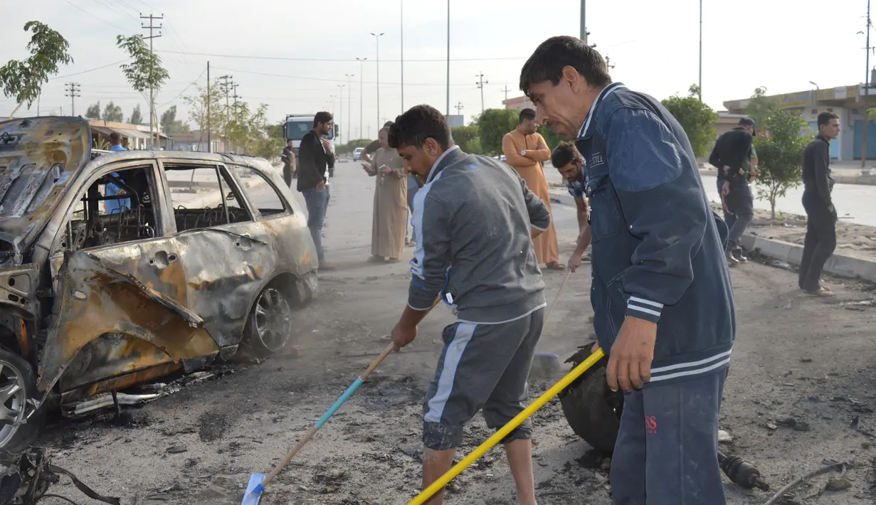 Warga membersihkan puing usai terjadi ledakan di Ameriyat Falluja, Irak, Jumat (18/11). Serangan yang diduga dilakukan ISIS ini sedikitnya menewaskan 17 orang dan belasan lainnya luka-luka. (Reuters/Osamah Waheeb) 