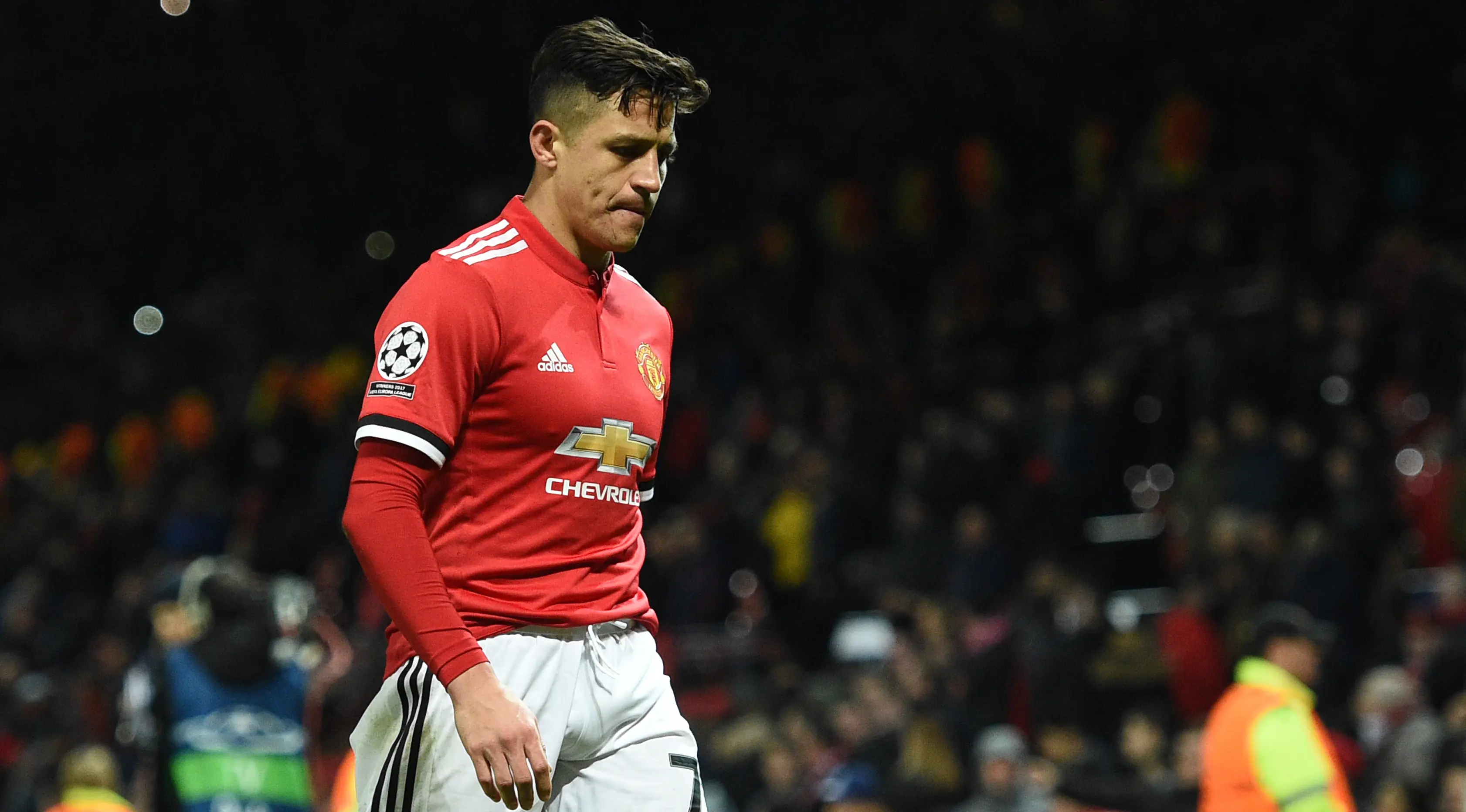 Striker Manchester United, Alexis Sanchez tertunduk sambil berjalan usai kalah dari Sevilla pada leg kedua 16 besar Liga Champions di Old Trafford, Selasa (13/3). Hasil ini membuat langkah Manchester United di Liga Champions terhenti. (Oli SCARFF/AFP)