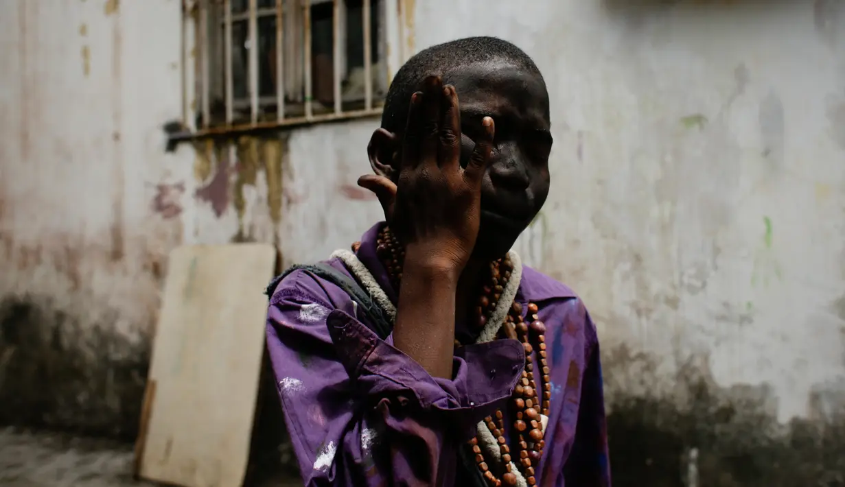 Seorang anak mengenakan pakaian yang menggambarkan "Cimarron" menggosok wajahnya dengan arang sebelum merayakan festival Congos and Devils di luar benteng San Jeronimo di Portobelo, Panama (18/3). (AP Photo / Arnulfo Franco)