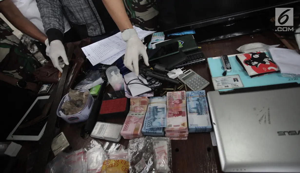 Sejumlah uang dan sebuah senjata api yang berhasil diamankan petugas saat penggerebekan di Kampung Ambon, Cengkareng, Jakarta, Rabu (24/1). Petugas juga berhasil mengamankan senjata api berikut amunisi, dan senjata tajam. (Liputan6.com/Arya Manggala)