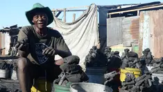 Seorang penjual arang menunjukan dagangannya di pasar sentral Les Cayes, Haiti, (25/1). Menteri Lingkungan Hidup Haiti akan membuat peraturan jaringan "hutan energi" yang menghasilkan kayu untuk arang dan kayu bakar. (AP/David McFadden)