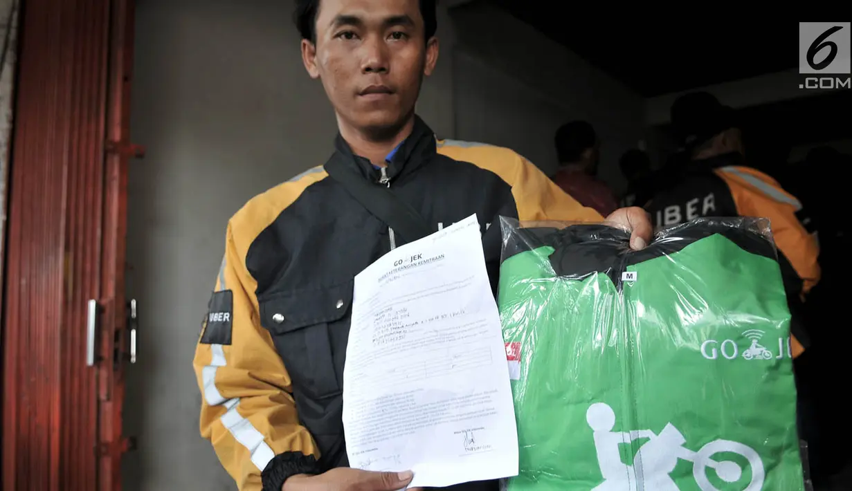 Mantan driver Uber menunjukkan jaket Go-Jek usai mendaftar di kantor cabang Gunung Sahari, Jakarta, Minggu (1/4). Informasi yang didapat, Go-Jek hanya menerima mitra yang sudah menjadi mitra Uber, bukan merekrut mitra baru. (Merdeka.com/Iqbal S Nugroho)
