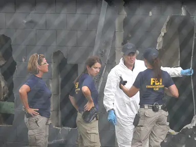 Petugas FBI menyelidiki dinding belakang klub malam gay Pulse di Kota Orlando, Florida, AS, Minggu (12/6). Penembakan brutal yang dilakukan Omar Mateen di klub tersebut menewaskan 50 orang dan melukai 53 lainnya. (Joe Raedle/Getty Images/AFP)