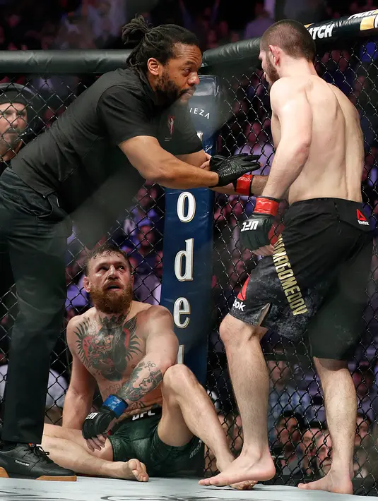 Khabib Nurmagomedov (kanan) ditahan oleh wasit Herb Dean setelah bertarung melawan Conor McGregor selama pertarungan UFC 229 di Las Vegas, AS (6/10). Nurmagomedov menang atas McGregor di ronde keempat. (AP Photo/John Locher)