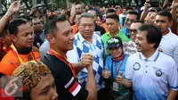 Calon Gubernur DKI Jakarta Agus Harimurti Yudhoyono melakukan salam komado dengan SBY saat menyapa warga Jakarta di Car Free Day (CFD), Senayan, Minggu (2/10). (Liputan6.com/Johan Tallo)