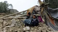 Duan anak laki-laki berada dekat rumah mereka yang rusak dalam gempa bumi di Distrik Spera, bagian barat daya Provinsi Khost, Afghanistan, 22 Juni 2022. Petugas PBB telah berusaha membantu situasi, namun upaya evakuasi terhambat oleh hujan deras. (AP Photo)