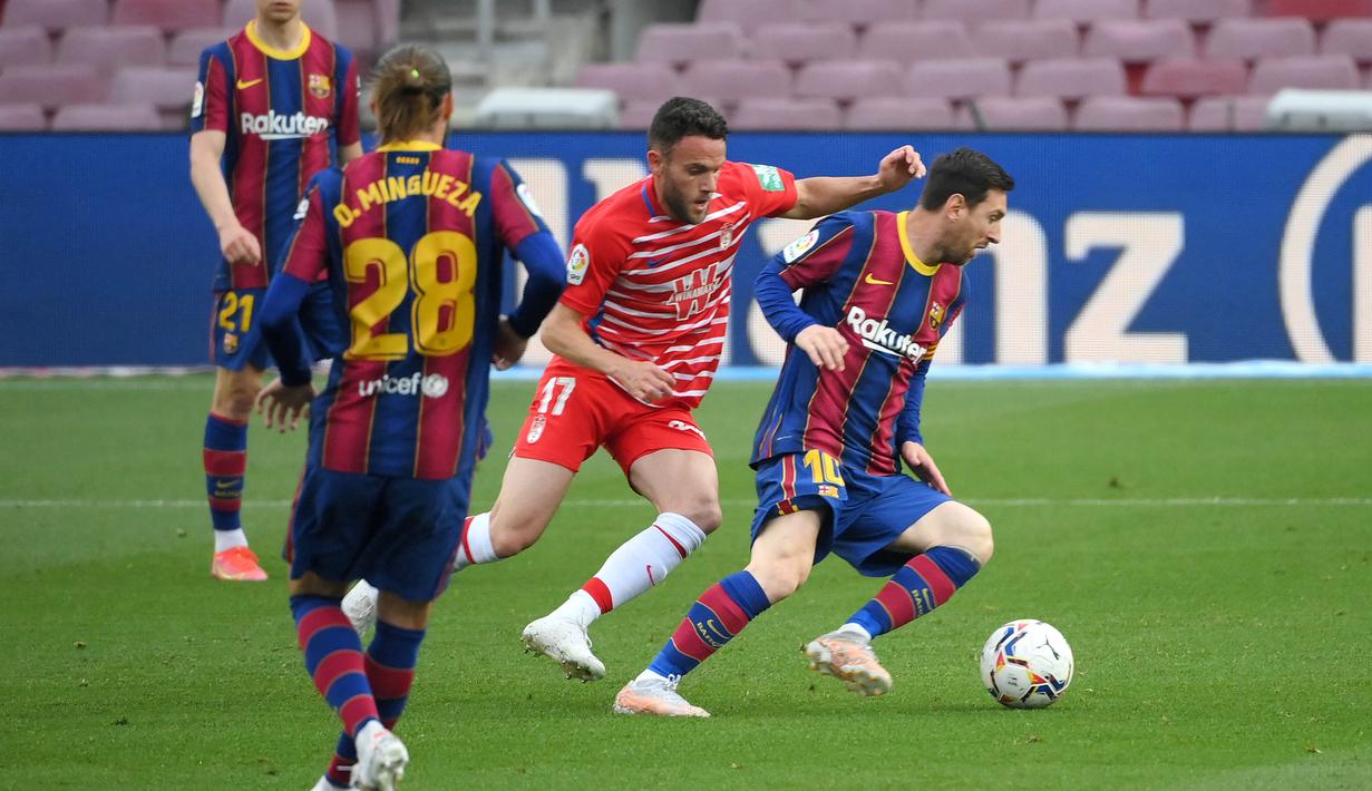 Striker Barcelona, Lionel Messi, berusaha melewati pemain Granada, Quini, pada laga Liga Spanyol di Stadion Camp Nou, Jumat (30/4/2021). Barcelona takluk dengan skor 1-2. (AFP/Lluis Gene)