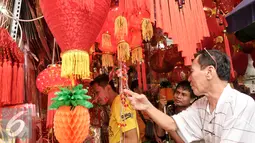 Calon pembeli memilih aksesoris Imlek di kawasan Petak Sembilan, Jakarta, Senin (23/1). Jelang hari raya Imlek 2017 pedagang angpao dan pernak-pernik mulai ramai di kawasan Petak Sembilan. (Liputan6.com/Yoppy Renato)