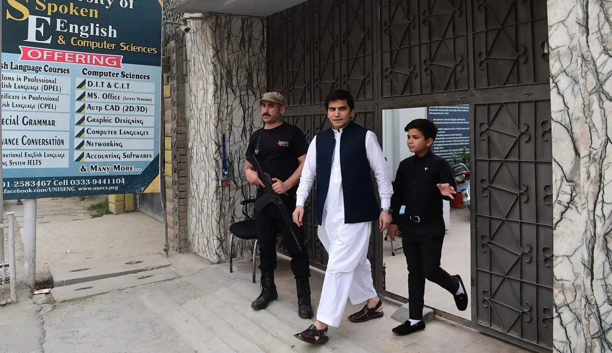 Motivator cilik Hammad Safi berjalan bersama gurunya di sebuah akademi bahasa di Peshawar, Pakistan (3/4). Saat memberi motivasi di depan umum, Hammad Safi selalu percaya diri dengan dandanan rapih dan elegan.  (AFP/Abdul Majeed)