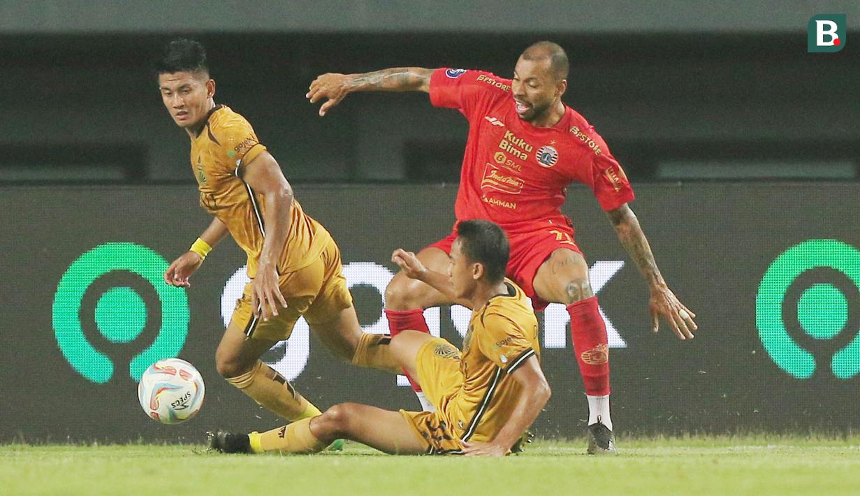 Pemain Persija Jakarta, Gustavo Almeida, terjatuh saat diadang pemain Bhayangkara FC, Sani Rizki dan Putu Gede pada laga BRI Liga 1 di Stadion Patriot Candrabhaga, Bekasi, Senin (27/11/2023). (Bola.com/M Iqbal Ichsan)