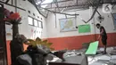 Penjaga sekolah berada di salah satu ruang kelas yang rusak akibat terjangan angin kencang di Sekolah Dasar Negeri (SDN) Pancoranmas 3, Depok, Jawa Barat, Minggu (24/7/2022). Puing-puing sisa bangunan yang ambruk pun masih berserakan di ruang kelas. (merdeka.com/Iqbal S. Nugroho)