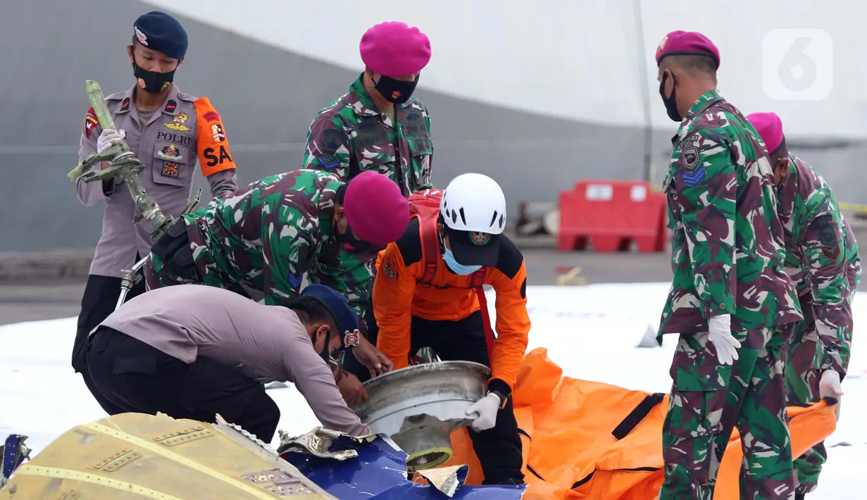 Polisi dan tentara mengumpulkan serpihan pesawat Sriwijaya Air SJ 182 di Dermaga JICT 2, Jakarta, Minggu (10/1/2021). Tim selam Marinir TNI AL menemukan dan mengevakuasi serpihan Sriwijaya Air SJ 182 yang kemudian diserahkan ke Basarnas, Kepolisian, serta KNKT. (Liputan6.com/Helmi Fithriansyah)