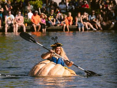Emma Gray, dari Tualatin, mendayung labu raksasa menuju garis finish dalam event West Coast Giant Pumpkin Regatta di Tualatin, Oregon, Amerika Serikat pada 16 Oktober 2022. Labu raksasa yang sudah dilubangi tersebut dijadikan kano untuk lomba mendayung. (Photo by Wesley Lapointe / AFP)