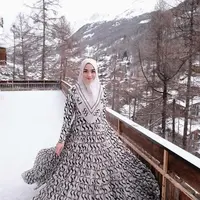 Berpose di hamparan salju Swiss, istri Rezky Aditya ini tampak anggun berbalut dress dan hijab monokrom.