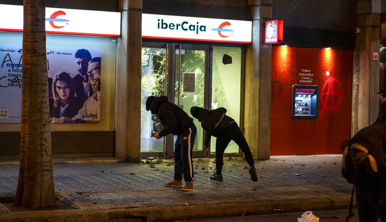 Demonstran menyerbu cabang bank saat memprotes penangkapan rapper Pablo Hasel di Barcelona, Spanyol, Selasa (16/2/2021). Aksi protes meletus di Spanyol setelah polisi menangkap Pablo Hasel yang menolak hukuman penjara karena menghina kerajaan dan memuji terorisme. (AP Photo/Emilio Morenatti)