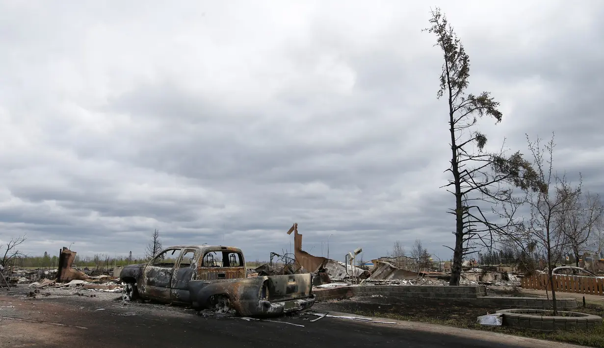 Sebuah kendaraan dan rumah terlihat hangus akibat kebakaran hutan di Beacon Hill dari Fort McMurray, Alberta, Kanada, (9/5). Sekitar 80 ribu warga Kanada terpaksa dievakuasi Akibat kebakaran dahsyat di seluruh kota ini. (REUTERS/Chris Wattie)