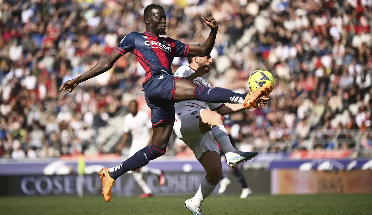 Pemain Bologna, Musa Barrow (kiri) berebut bola dengan pemain AC Milan, Alessandro Florenzi pada laga lanjutan Liga Italia 2022/2023 di Renato-Dall'Ara Stadium, Bologna, Minggu (16/04/2023) WIB. Laga berakhir dengan skor imbang 1-1. (AP Photo/LaPresse/Massimo Paolone)