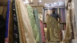 Pekerja menyusun bahan kain di Pasar Tanah Abang, Jakarta, Sabtu (27/11/2021). Utilisasi industri tekstil dan produk tekstil dalam negeri menunjukkan kinerja yang positif menjelang akhir 2021. Utilisasi industri itu berada di posisi 80 - 85 persen pada awal kuartal IV/2021. (Liputan6.com/Angga Yunia