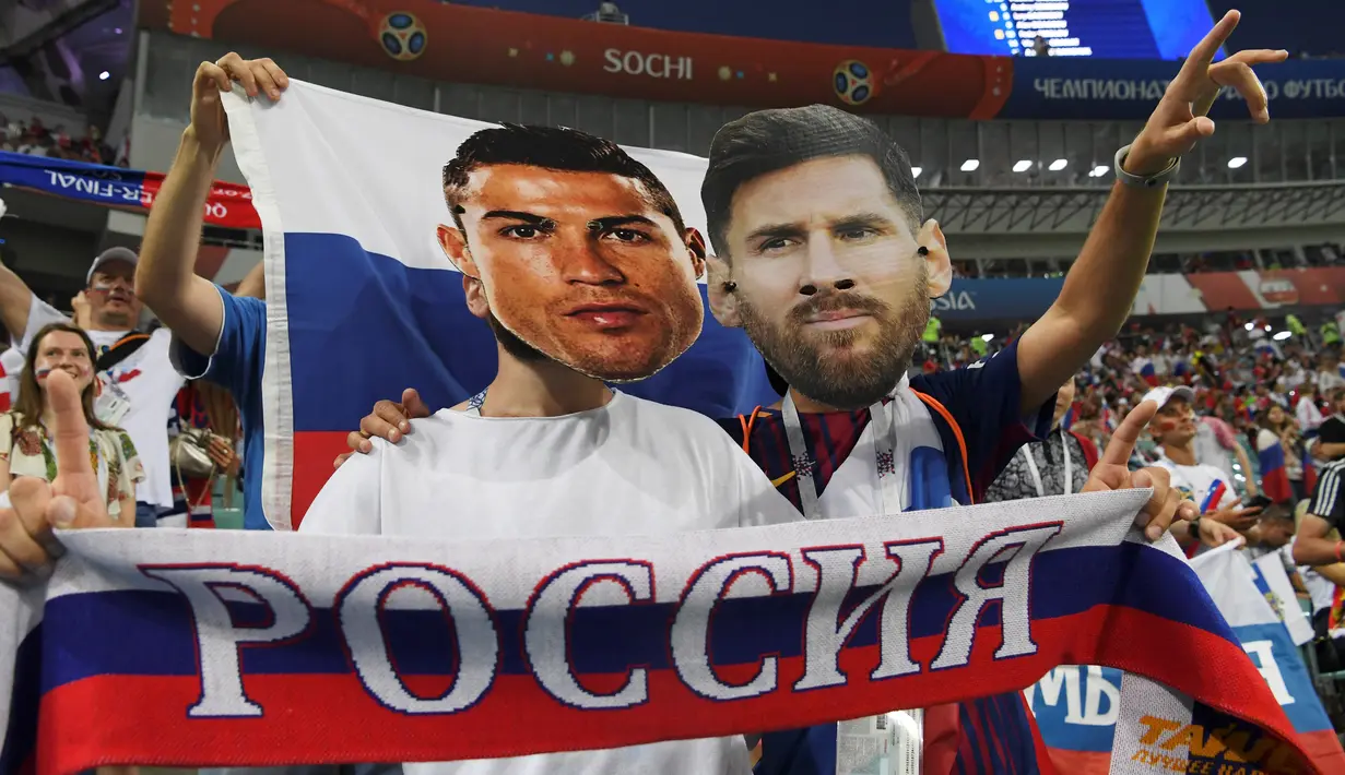 Suporter berpose memakai topeng bintang Portugal, Cristiano Ronaldo dan bintang Argentina, Lionel Messi sebelum laga babak perempat final Piala Dunia 2018 antara Rusia dan Kroasia di Stadion Olimpiade Fisht, Sabtu (7/7). (AFP PHOTO/Kirill KUDRYAVTSEV)