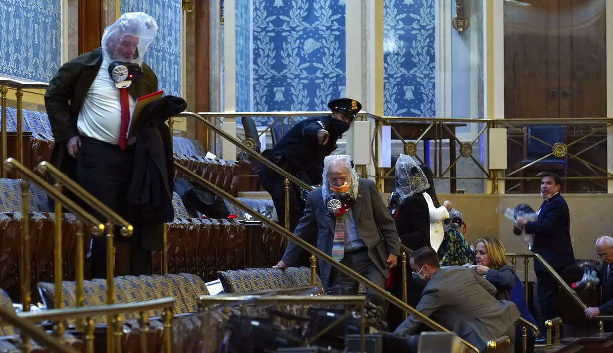 Orang-orang berlindung dalam galeri House saat pengunjuk rasa mencoba masuk ke House Chamber di Gedung Capitol Hill, Washington DC, Amerika Serikat, Rabu (6/1/2021). Kericuhan terjadi saat massa pendukung Donald Trump merangsek masuk ke dalam Gedung Capitol Hill. (AP Photo/Andrew Harnik)
