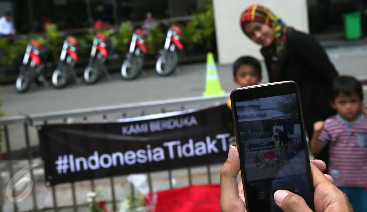 Layar ponsel menunjukkan foto warga yang tengah mengabadikan gambar di depan Menara Cakrawala, Jakarta, Sabtu (16/1). Lokasi teror di kawasan Sarinah Thamrin terus didatangi warga untuk mengabadikan diri atau foto selfie. (Liputan6.com/Faizal Fanani)