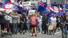 Demonstran berbaris di sepanjang Lambton Quay sebelum berkumpul di gedung Parlemen Selandia Baru, di Wellington, Selasa (9/11/2021). Ribuan warga Selandia Baru berdemonstrasi memprotes kebijakan vaksin covid-19 dan penguncian (lockdown) yang diterapkan negara itu. (Mark Mitchell/NZ Herald via AP)