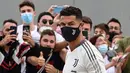 Striker Juventus, Cristiano Ronaldo disambut penggemar setibanya di  gedung pusat medis Juventus di Turin, Italia, Senin (26/7/2021). Cristiano Ronaldo menjalani tes medis menjelang musim keempatnya bersama klub Seria A itu. (Miguel MEDINA/AFP)