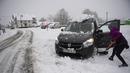 Seorang perempuan membersihkan salju dari mobilnya di Burguete, Spanyol utara, Senin, 16 Januari 2023. Pihak berwenang telah mengumumkan salju dan suhu sangat rendah selama beberapa hari ke depan di seluruh bagian utara negara itu. (AP Photo/Alvaro Barrientos)