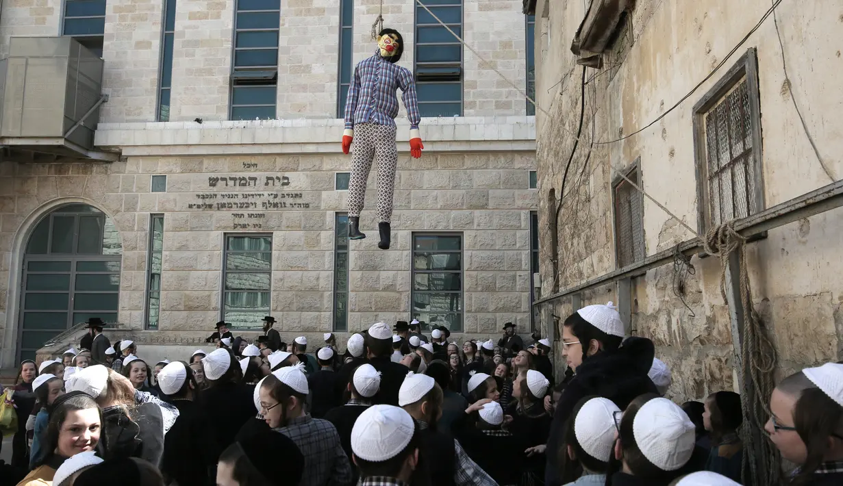 Anak-anak Yahudi ultra-Ortodoks melihat boneka yang melambangkan figur Haman yang digantung selama perayaan purim di Yerusalem (8/3). (AFP/Menahem Kahana)