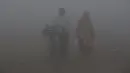 Warga India melintas saat polusi asap tebal menyelimuti sepanjang tepi sungai Yamuna di Agra, Uttar Pradesh, Rabu (3/1). Polusi udara di India kebanyakan berasal dari kendaraan diesel, tambang batu bara, dan pembakaran lahan. (XAVIER GALIANA / AFP)