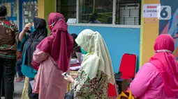 Para guru antre untuk menjalani vaksinasi COVID-19 di SMA 70, Jakarta, Rabu (25/2/2021). Sebanyak 600 orang dari profesi guru, tenaga kependidikan, dan dosen akan divaksin COVID-19 hari ini. (Liputan6.com/Faizal Fanani)