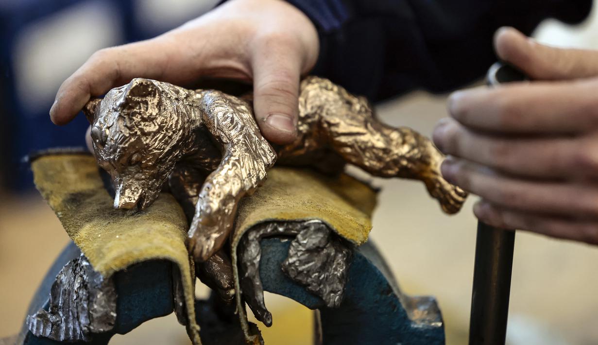 Seorang perajin mengerjakan trofi Berlinale Bear dari Festival Film Internasional Berlin ke-72 yang akan datang di pengecoran Noack di Berlin, pada 25 Januari 2022. Kompetisi film Berlin edisi 2022 akan berlangsung dari 10 - 16 Februari sebagai acara tatap muka. (Hannibal Hanschke/POOL/AFP)