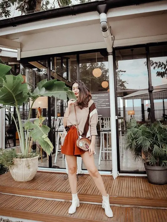Inspirasi outfit hang out, tiru gaya kasual Conchita Caroline dengan kombinasi sweater rajut, hot pants, dan sock boots. Lengkapi penampilanmu dengan mini sling bag. (Foto: Instagram/conchizzlin).