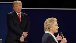 Ekspresi Donald Trump yang berdiri belakang rivalnya, Hillary Clinton selama debat Capres AS putaran kedua di Washington University, St Louis, AS, Minggu (9/10). Bahasa tubuh trump ini memicu keheranan dan ejekan di media sosial. (AP Photo/Julio Cortez)