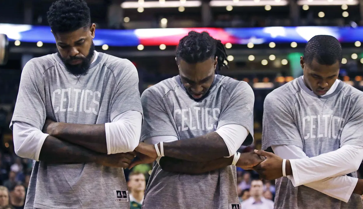 Para pemain Boston Celtics,  Amir Johnson, Jae Crowder, Gerald Green berpegangan tangan saat lagu kebangsaan dikumandangkan sebelum melawan Brooklyn Nets pada laga NBA preseason basketball game, Boston, Selasa (18/10/2016) WIB. (AP/Charles Krupa)