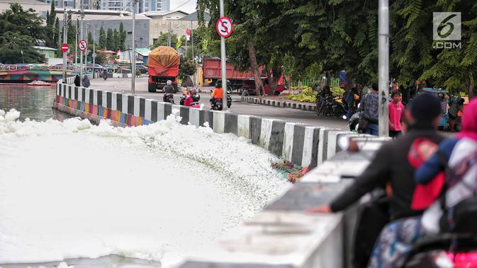 Warga melihat kondisi Kali Item yang berbusa di Kemayoran, Jakarta, Selasa (1/1). Tumpukan busa menjadi tontonan warga yang melintas. (Liputan6.com/Faizal Fanani)