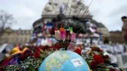 Karangan bunga di atas globe di Place de la Republique, Paris (24/12/2015). Aksi simpatik ini untuk mengenang tragedi serangan Paris yang menewaskan 130 orang. (AFP Photo/Miguel Medina)