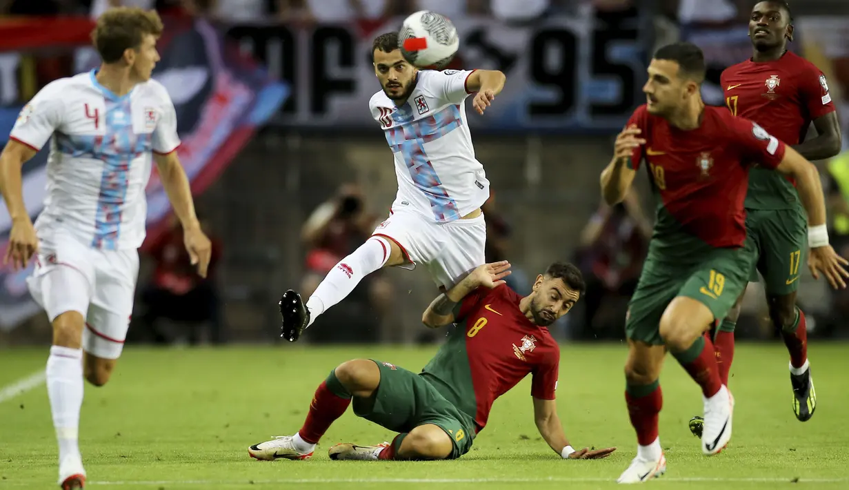 Gelandang Timnas Portugal, Bruno Fernandes (bawah) berusaha menghadang laju gelandang Luksemburg, Danel Sinani pada laga Grup J Kualifikasi Euro 2024 di Estadio Algarve, Selasa (12/9/2023) dini hari WIB. (AP Photo/Joao Matos)