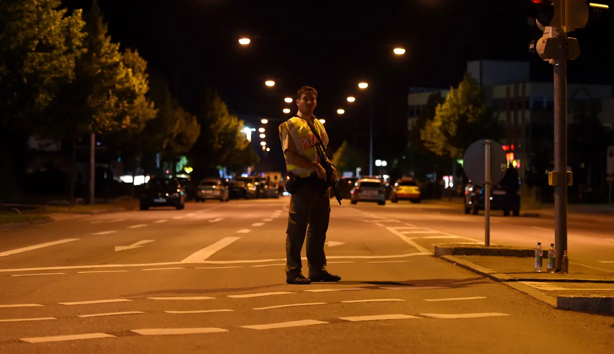 Seorang polisi berjaga di sebuah jalan di dekat pusat perbelanjaan Olympia Einkaufzentrum (OEZ) di Munich, Jerman (22/7). Penembakan ini hanya berselang tiga hari setelah terjadinya penyerangan di kereta api Jerman. (AFP PHOTO/Christof Stache)